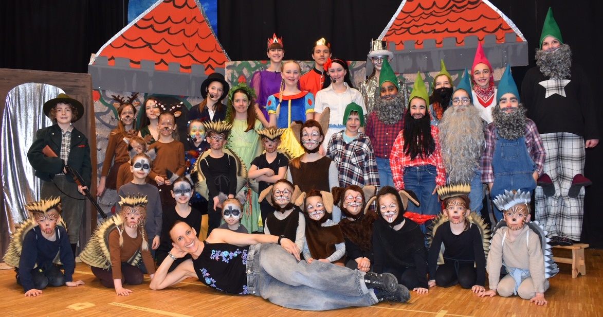 Gruppenbild von 35 verkleideten Kindern und Jugendlichen und einer Erwachsenen auf der Theaterbühne