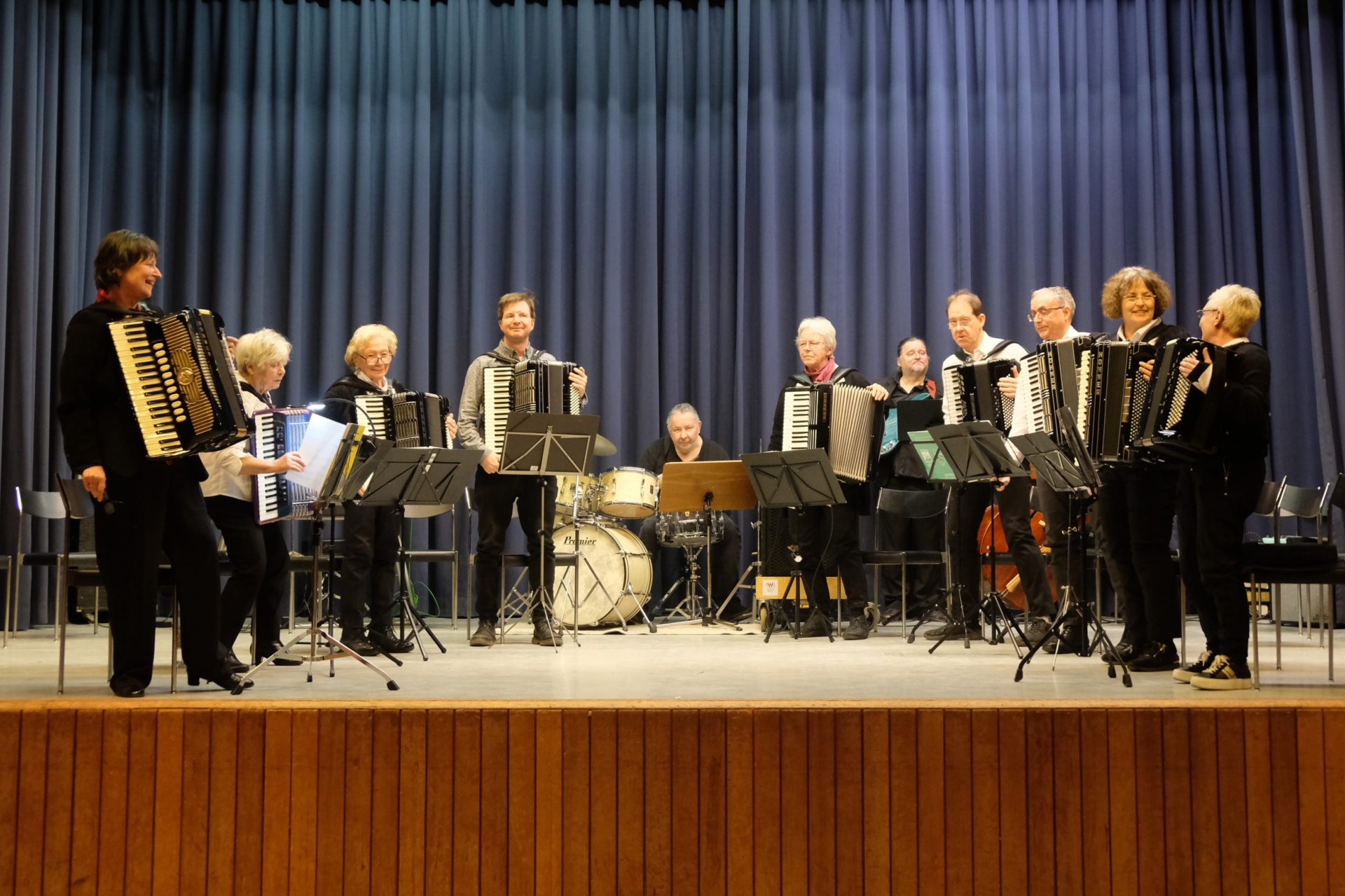 Die 8 Akkordeonisten und die Bassisten nehmen stehend den Applaus entgegen. Dahinter noch der Schlagzeuger, der bei diesem Werk nicht im Einsatz war und ebenfalls stehend der E-Bassist.