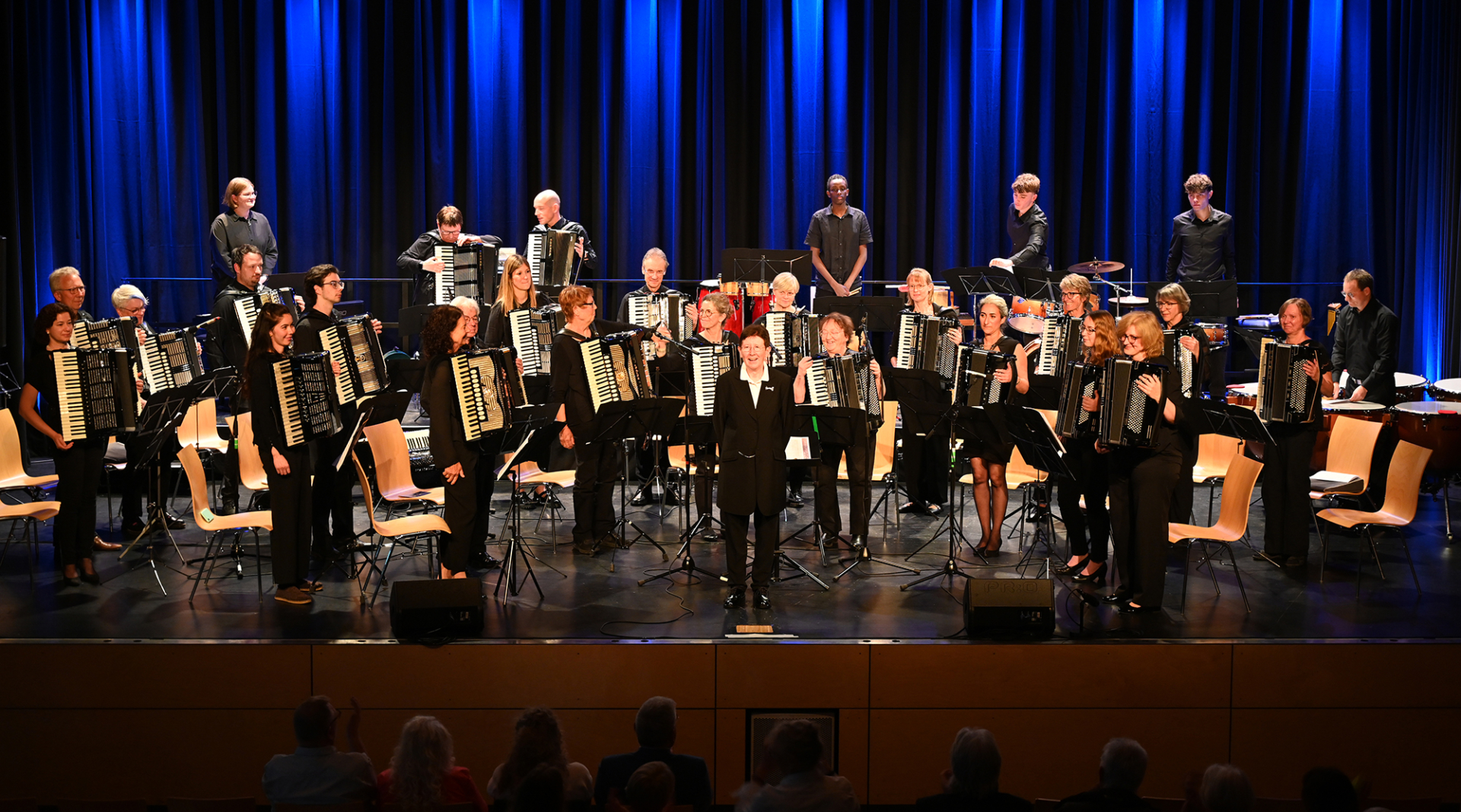 Dirigentin Karin Berger mit dem Haupt-Orchester, stehend mit Akkordeons, nach einem sehr gelungenen Auftritt, beim sausenden Applaus der begeisterten Zuhörer.