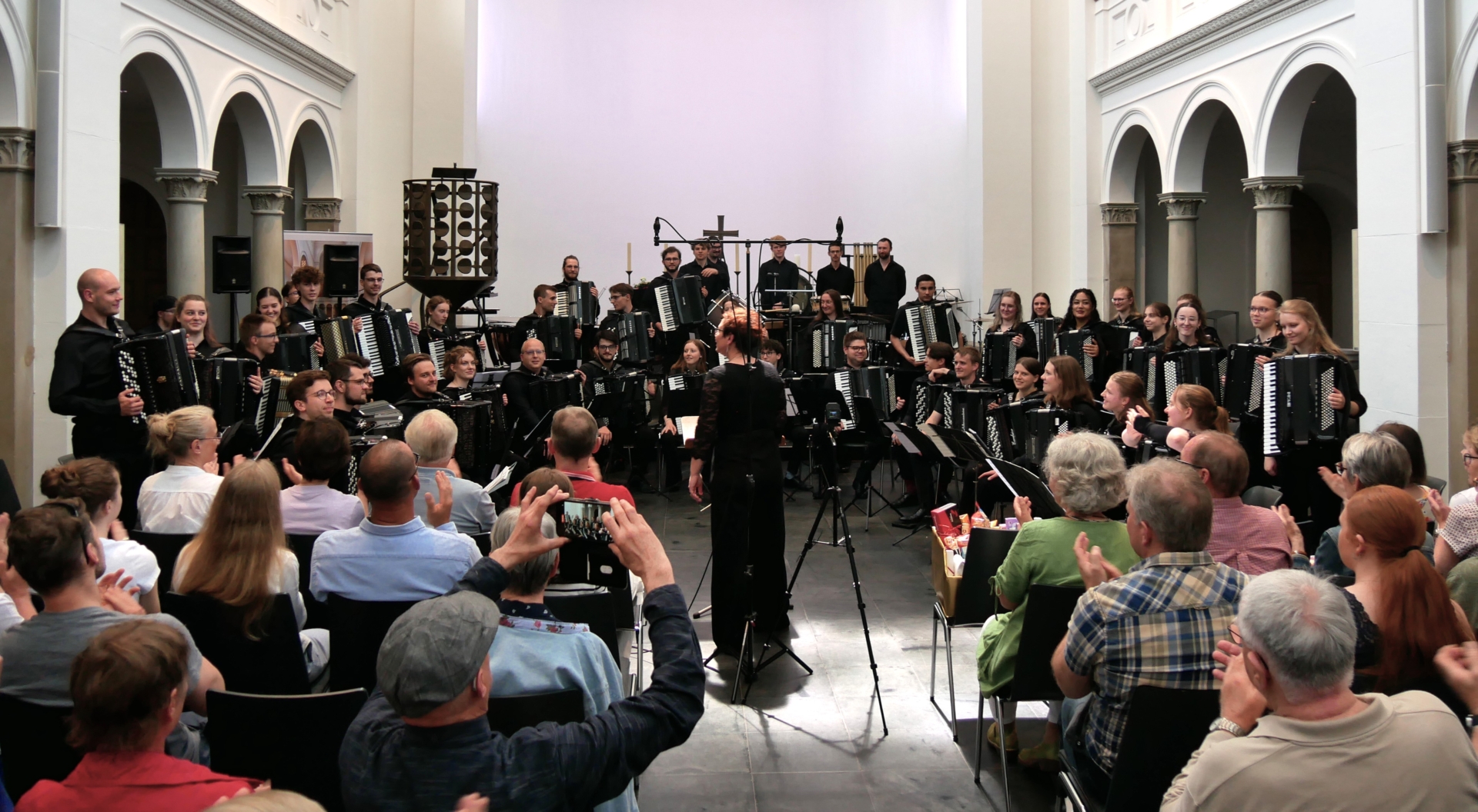 50 junge Akkordeonistinnen und Akkordeonisten im Altarraum der Kirche - Dirigentin Yvonne Glur hat die hinteren Reihen aufstehen lassen, so dass fast alle Gesichter zu sehen sind.