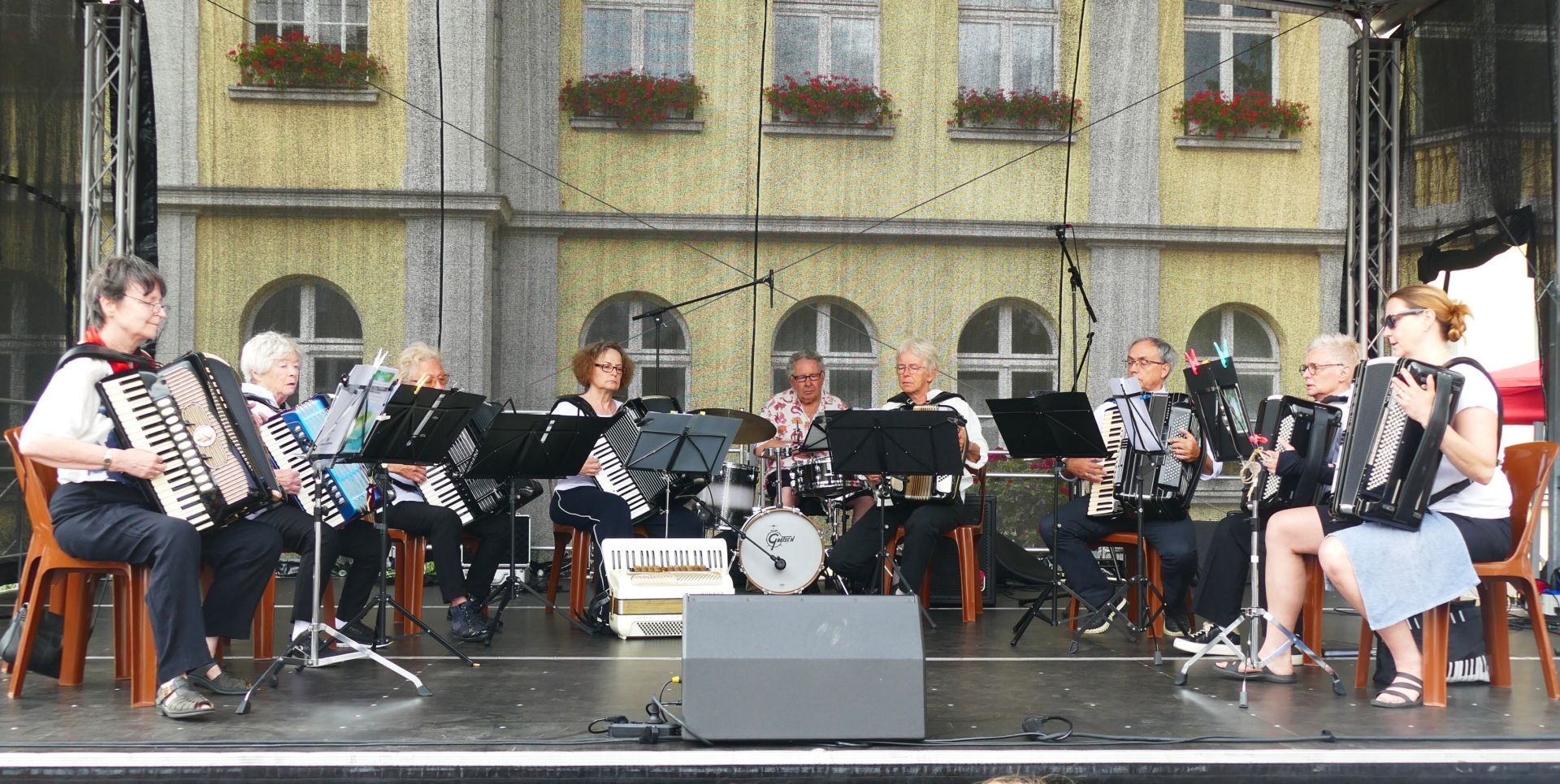 Auf der Bühne vor dem Alten Rathaus der Stadt Wesseling spielt das neunköpfige Ensemble im Halbkreis.